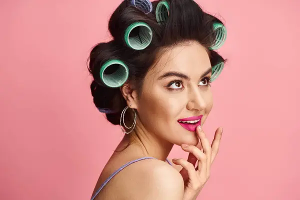 A stunning woman with curlers in her hair poses for the camera against a vibrant backdrop. — Stock Photo