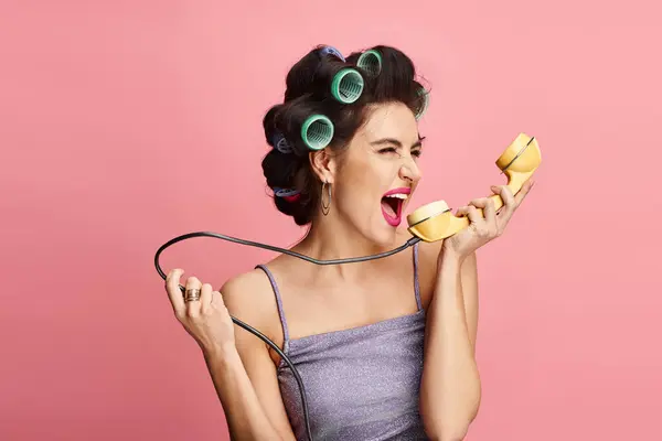 Stylish woman in curlers posing with retro phone. — Stock Photo