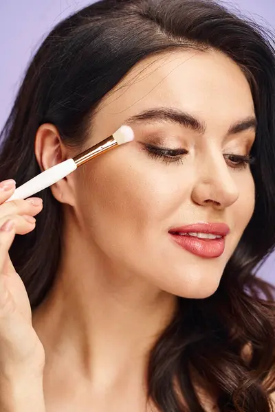 A woman with a brush, having fun and applying makeup to enhance her natural beauty. — Stock Photo