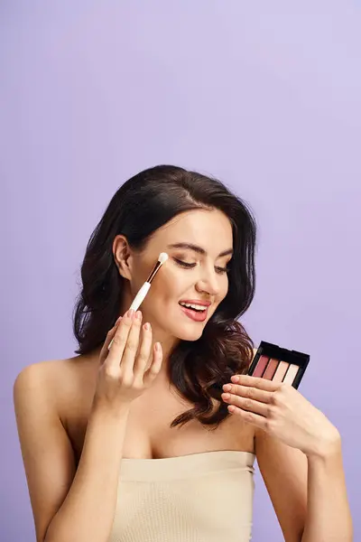 A woman gracefully holds a brush and powder for her makeup routine. — Stock Photo