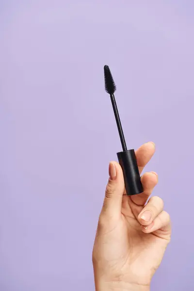 A woman enhances her natural beauty with black mascara in hand. — Stock Photo