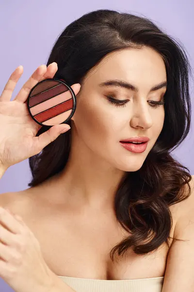 A natural beauty woman gracefully applying makeup with a palette. — Stock Photo