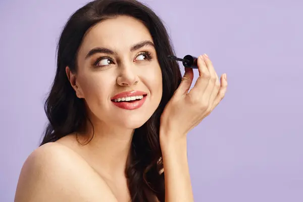 Une femme avec une beauté naturelle tient un mascara dans sa main. — Photo de stock