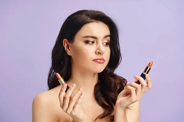 A woman with natural beauty holds two vibrant lipsticks in her hands. — Stock Photo