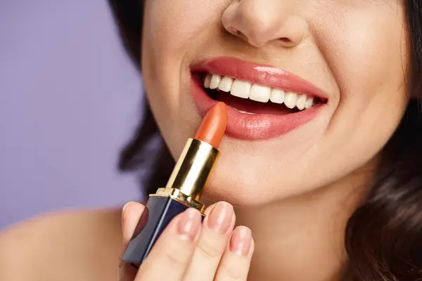 A beautiful woman enhancing her appearance by applying lipstick to her lips. — Stock Photo