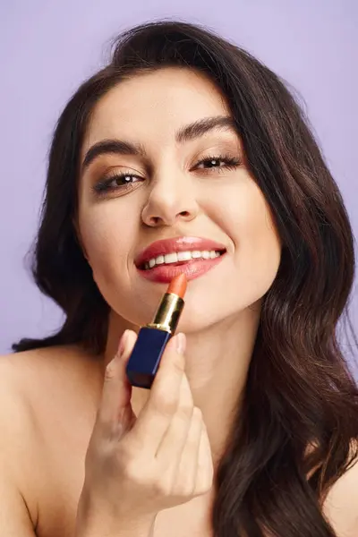 Mujer sosteniendo un lápiz labial en su mano, aplicando maquillaje con belleza natural. - foto de stock