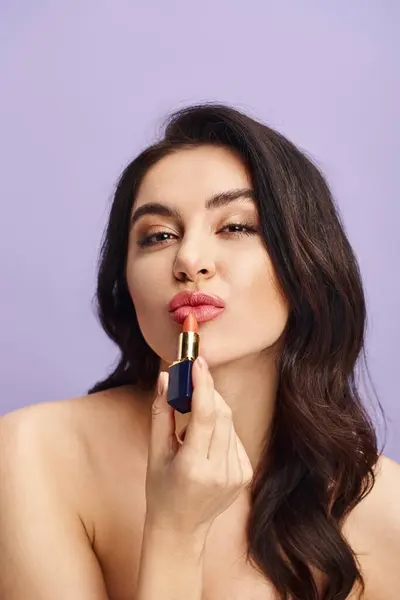 A woman holding a lipstick in front of her face, enhancing her natural beauty with makeup. — Stock Photo