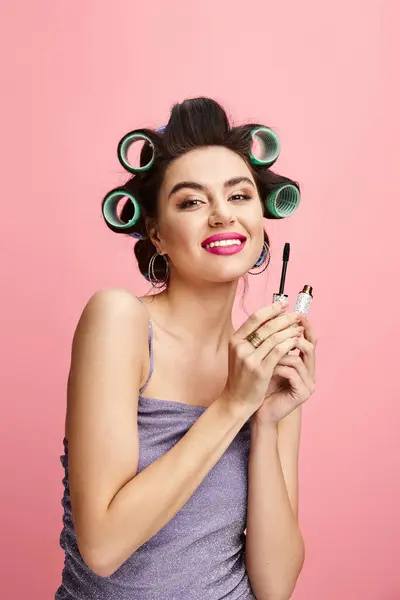 Femme avec des bigoudis tient un maskara. — Photo de stock