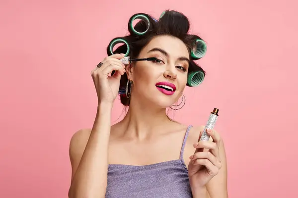 Stylish woman with curlers in hair holding a maskara. — Stock Photo