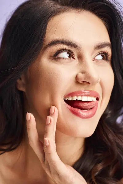 A woman smiles with makeup and with her hand near her face. — Stock Photo
