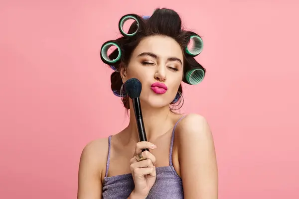 Eine Frau mit Lockenwicklern im Haar hält einen Pinsel in der Hand. — Stockfoto