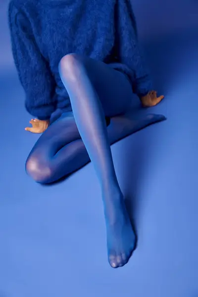 A young womans legs in vibrant blue stockings against a blue background, exuding grace and elegance. — Stock Photo