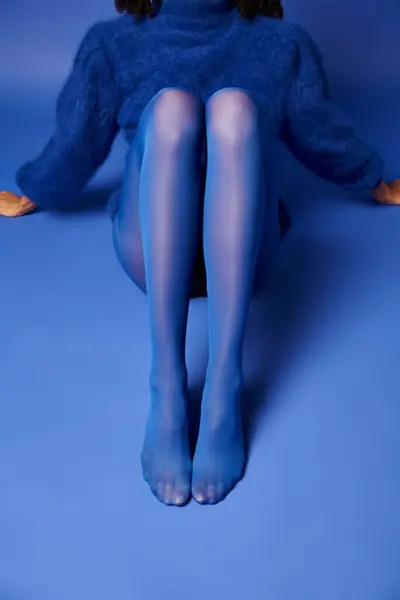 Una joven con un llamativo vestido azul posa sentada en el suelo con un aire de serenidad y elegancia. - foto de stock