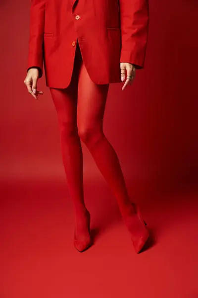 A woman wearing a vibrant red suit and tights stands in a bold and striking pose. — Stock Photo