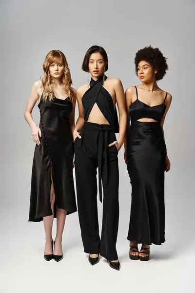 Trois belles femmes, représentant la diversité, debout élégamment sur un fond de studio gris. — Photo de stock