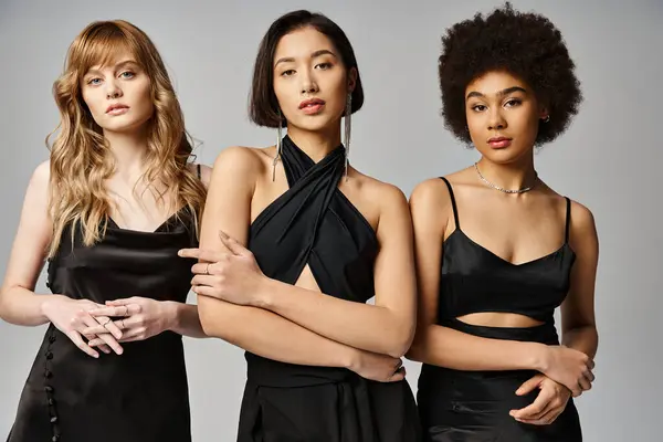 Un gruppo eterogeneo di tre donne, caucasica, asiatica e afroamericana, in piedi insieme su uno sfondo grigio studio. — Foto stock