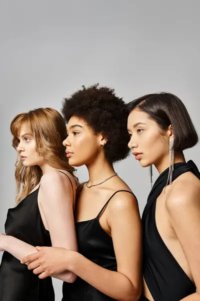 Um grupo diversificado de mulheres elegantes de diferentes etnias de pé juntos em harmonia contra um fundo de estúdio cinza. — Fotografia de Stock