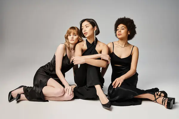 Three women of different ethnicities sitting elegantly side by side, showcasing beauty and unity. — Stock Photo