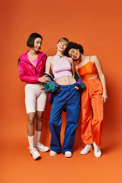 Um grupo de multiculturais jovens mulheres de pé juntos contra um fundo laranja, exalando beleza e unidade. — Fotografia de Stock