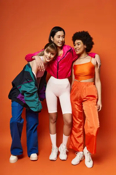 Un gruppo di donne multiculturali, tra cui caucasica, asiatica e afroamericana, stare insieme armoniosamente su uno sfondo arancione. — Foto stock