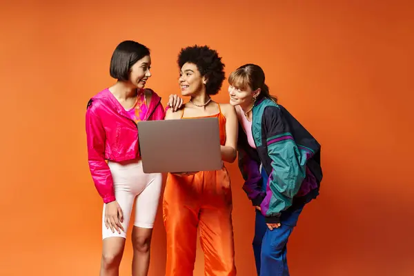 Três mulheres - caucasianas, asiáticas, afro-americanas - se unem contra um fundo de estúdio laranja, irradiando beleza e diversidade. — Fotografia de Stock