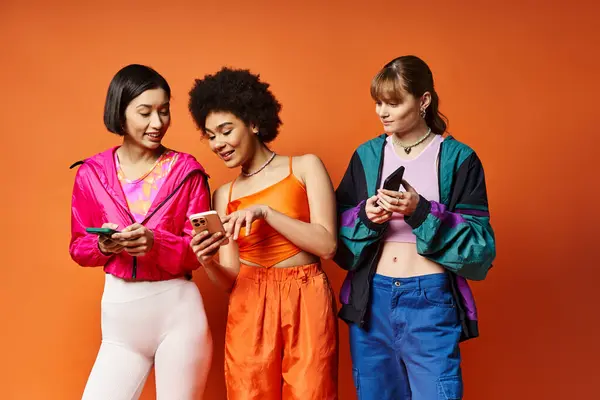 Trois femmes multiculturelles debout ensemble, absorbées dans leurs téléphones. — Photo de stock