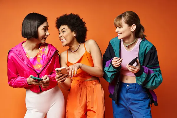 Trois femmes de différentes ethnies debout ensemble, regardant un écran de téléphone cellulaire intensément. — Photo de stock