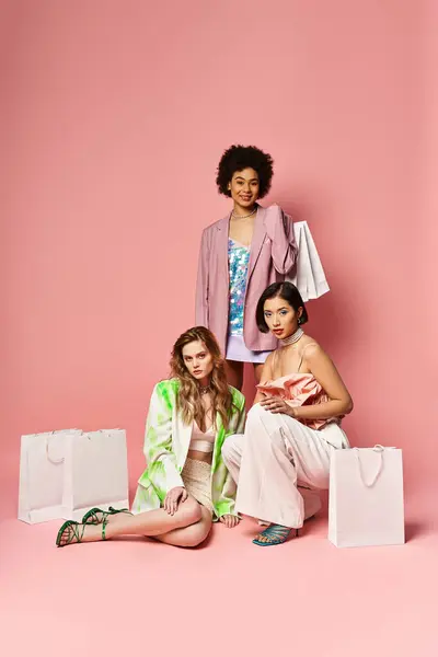 A diverse group of women peacefully sitting on the ground in front of a soft pink wall on a beautiful spring day. — Stock Photo