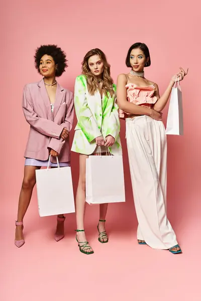 Groupe diversifié de femmes debout avec des sacs à provisions sur un fond rose. — Photo de stock