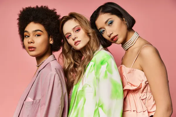 Diverse group of women in colorful outfits standing together against a pink backdrop, celebrating unity and beauty. — Stock Photo