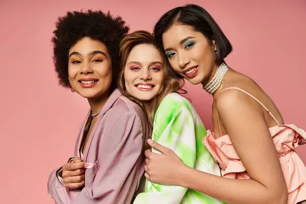 Three beautiful women of different ethnicities standing in unity, showcasing diversity on a pink background. — Stock Photo