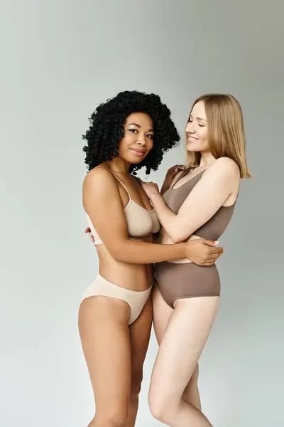 Two diverse women stand confidently in cozy pastel underwear. — Stock Photo