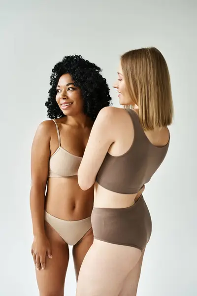 Zwei unterschiedliche Frauen in kuscheliger Pastellunterwäsche stehen nebeneinander. — Stockfoto