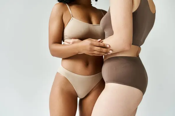 Two diverse women stand next to each other in cozy pastel underwear. — Stock Photo