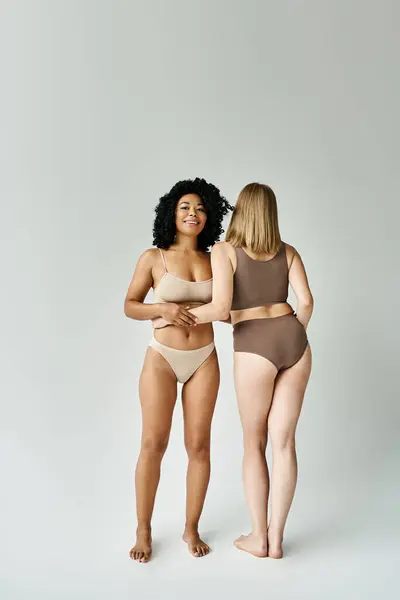 Duas belas mulheres diversas em costureira pastel acolhedor ficar ao lado um do outro. — Fotografia de Stock