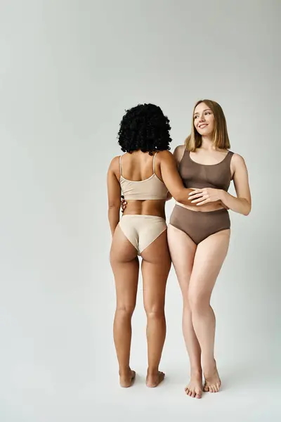 Two diverse women in cozy pastel bikinis standing side by side. — Stock Photo