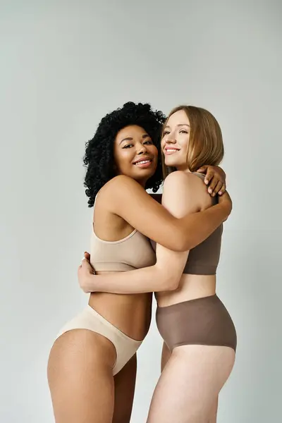 Zwei schöne Frauen in kuscheliger Pastellunterwäsche umarmen sich herzlich. — Stockfoto