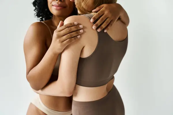 Two diverse women in cozy pastel underwear sharing a warm embrace. — Stock Photo