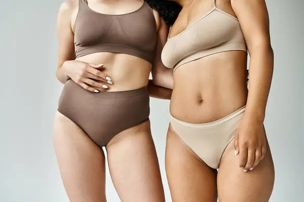 Two beautiful diverse women standing in cozy pastel underwear. — Stock Photo