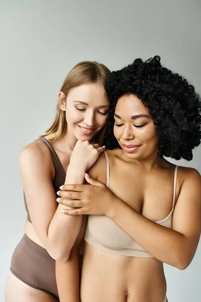 Two diverse women in pastel underwear tenderly hugging each other. — Stock Photo