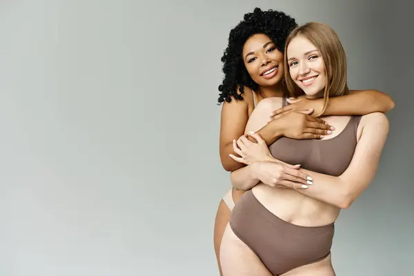 Duas mulheres bonitas e diversas em roupa de banho pastel abraçando-se calorosamente. — Fotografia de Stock