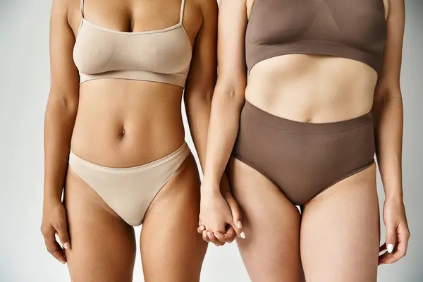 Two diverse women stand peacefully in cozy pastel underwear. — Stock Photo