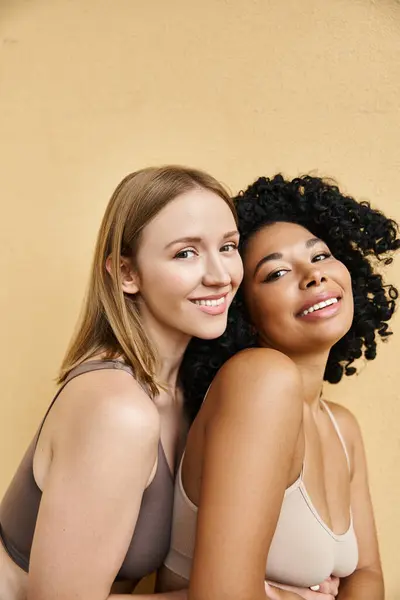 Two beautiful diverse women in cozy pastel underwear pose gracefully together. — Stock Photo