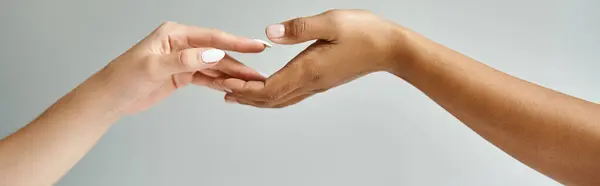 Two beautiful diverse women hold hands, fingers entwined in a gentle embrace. — Stock Photo