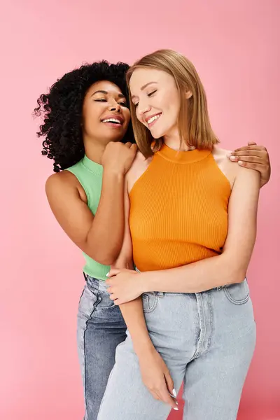 Two attractive diverse women in cozy casual attire hug each other warmly, smiling with joy. — Stock Photo