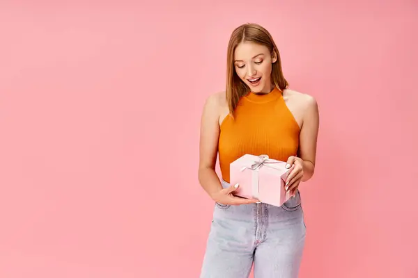 Женщина в удобной повседневной одежде держит розовую подарочную коробку в руках. — стоковое фото