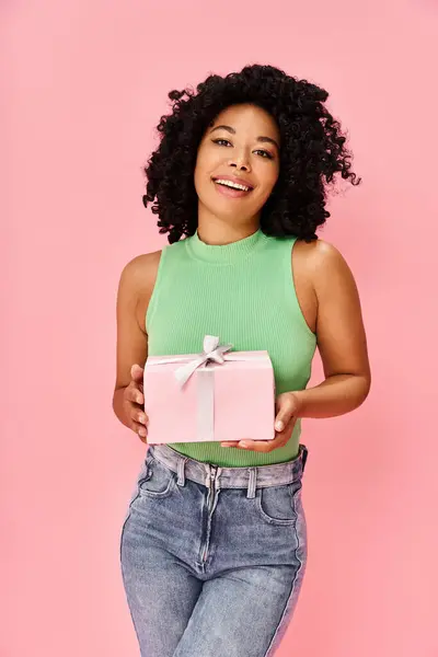 A woman in a green shirt holds a pink gift box. — Stock Photo