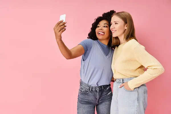 Deux jolies femmes diverses en tenue décontractée prenant un selfie avec un téléphone portable. — Photo de stock