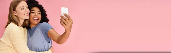 Two diverse women in casual attire taking a selfie with a cell phone. — Stock Photo