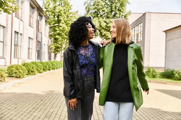 Two attractive diverse women in cozy casual attire standing next to each other on a sidewalk. — Stock Photo